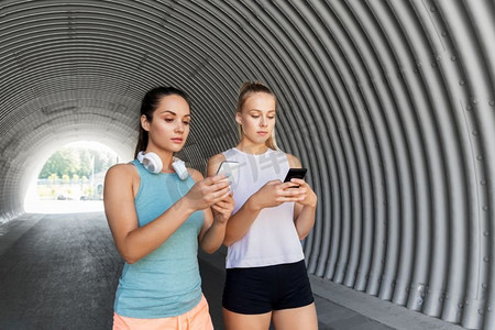 手机app生活摄影照片_健身，运动和健康的生活方式概念—年轻女性或女性朋友与智能手机。使用智能手机的女性或女性朋友