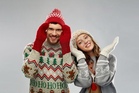 圣诞节，冬装和假日概念—在丑陋毛衣党的快乐夫妇肖像。快乐的夫妇在圣诞节丑陋的毛衣党