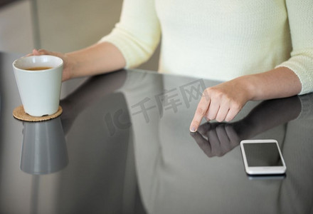 科技与人的概念-女性使用黑色互动面板喝咖啡的特写。喝咖啡的女人使用黑色互动面板