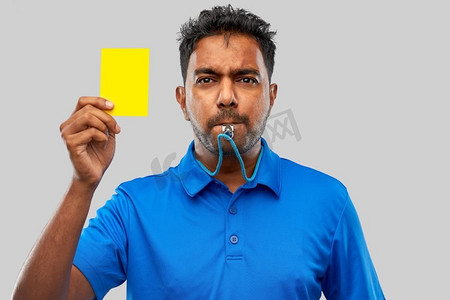 运动口哨摄影照片_运动、谨慎、游戏和足球概念——印度裁判吹口哨并出示黄牌。印度裁判吹口哨出示黄牌