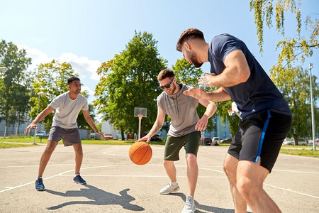街头篮球摄影照片_体育、休闲游戏和男性友谊概念—一群男人或朋友打街头篮球。一群男性朋友打街头篮球
