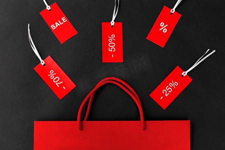 销售和出口概念—红色购物袋和标签与折扣标志在黑色背景。红色购物袋和带有折扣标志的标签