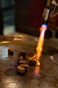 肉制摄影照片_铁板烧牛肉食谱日本烤牛肉在带刮刀和煤气灶的平底锅上烹调