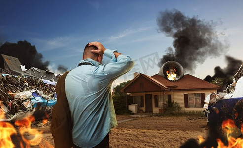 一个人正在看房子附近的飞机残骸，那里正在燃烧。’飞机坠毁后看房子的人