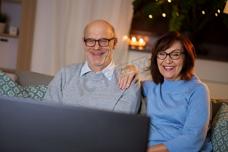 假日，饮料和人的概念—快乐微笑的老年夫妇在家里看电视晚上。快乐的老年夫妇看电视在家