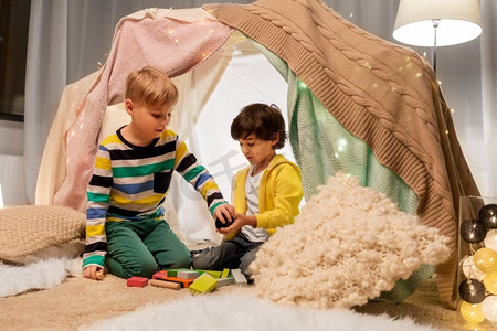童年，hygge和友谊概念—男孩玩玩具块在孩子帐篷或帐篷在家里。男孩玩玩具块在孩子帐篷在家里