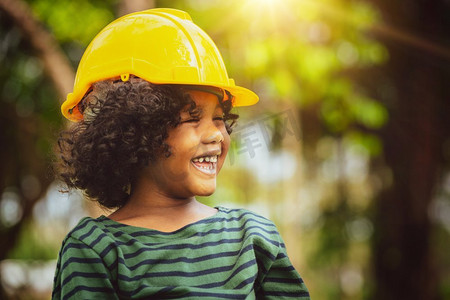 快乐的工程师小男孩戴着黄色安全帽，幸福地笑着。教育和学习理念。