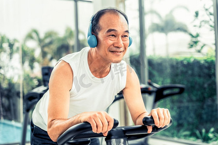 老年男子在健身中心的自行车器材上锻炼身体。成熟健康的生活方式..老年人在健身中心的自行车机上锻炼