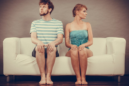 糟糕的感情观念。男人和女人意见相左。年轻夫妇争吵后坐在沙发上冒犯在家里