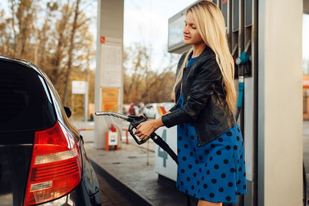 有枪的女人在加油站给汽车加油,加油.美女轿车