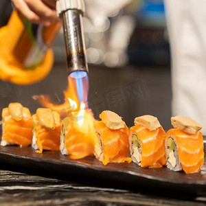 厨师烹饪三文鱼鹅肝酱卷，融合日本料理食物，使用燃气炉火炬。