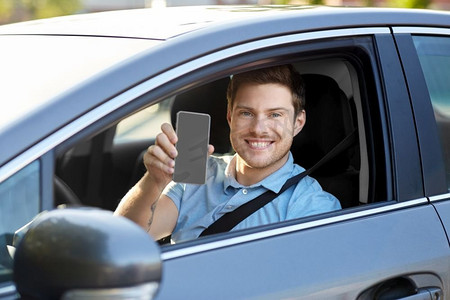 交通、驾驶和科技概念--男人或汽车司机展示智能手机。展示智能手机的男人或汽车司机