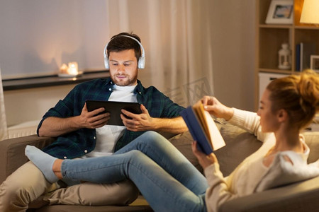 休闲与人的理念-晚上在家搭配平板电脑、耳机和书籍。在家里搭配平板电脑和书本