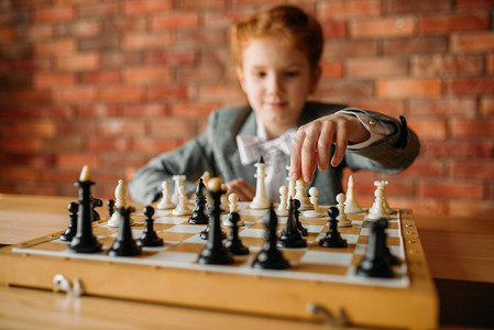 棋盘签到摄影照片_聪明的女学生，在桌上下棋。小女孩在棋盘上，女孩子玩逻辑游戏。聪明的女学生，桌上的象棋手