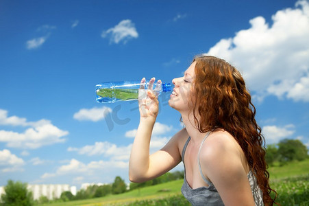 侧写中的女子在公园里喝瓶子里的水