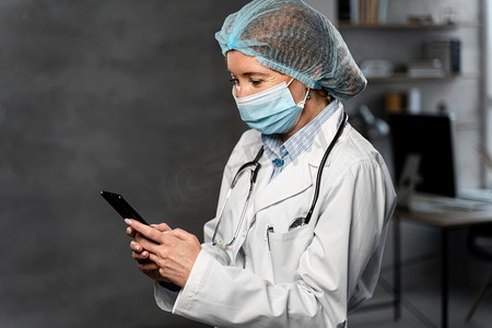 带医用口罩发网手持智能手机的女医生侧视防静电帽医生