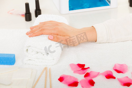 女人的手在毛巾上，等待凝胶混合美甲。美容养生水疗护理理念。女人手放在毛巾上，旁边的美甲套装