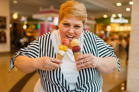 在快餐店吃两个冰淇淋的胖女人。超重女性吃冰淇淋，肥胖问题