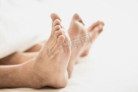情侣们在卧室里赤脚盖着毯子。性爱的假期和快乐。情人节主题。假日早晨主题