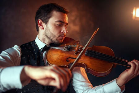 提琴手摄影照片_男提琴手用小提琴演奏古典音乐的肖像。带着乐器的小提琴手