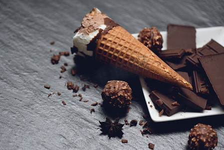 甜酒吧摄影照片_冰淇淋甜筒与巧克力棒和球在黑暗背景/冰淇淋香草覆盖的巧克力冷冻冰棒甜的甜点或小吃