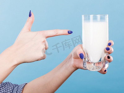 拿牛奶摄影照片_健康饮品，营养好，奶制品理念。女人手里拿着一杯牛奶。女人手拿着牛奶杯