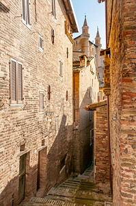 意大利马尔凯文艺复兴时期的乌尔比诺小镇。从意大利马尔凯乌尔比诺市的一条狭窄街道上看杜卡莱宫(Palazzo Ducale)的景色