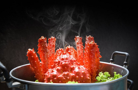 麻辣鱼火锅摄影照片_阿拉斯加国王蟹在蒸锅海鲜和生菜蔬菜的熟蒸笼食物与黑暗背景/红蟹北海道