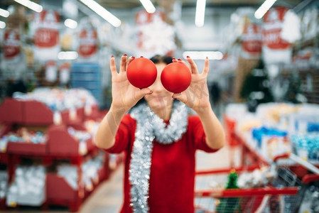 年轻女子在商店展示圣诞树球，家庭传统。12月购物的节日商品和装饰品