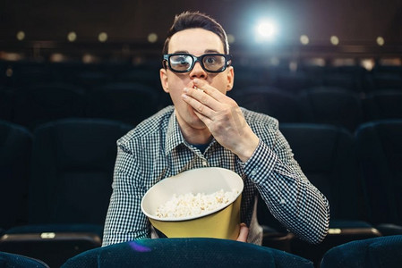 一个拿着爆米花的青少年在电影院里看电影着迷了。娱乐行业娱乐时间