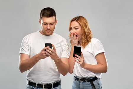 与人连接摄影照片_技术和人的概念—愉快的夫妇在白色t恤与智能手机在灰色背景。快乐的夫妇在白色T恤与智能手机