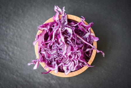 卷心菜紫色/切碎的红卷心菜片在一个木碗和黑暗背景，顶视图 
