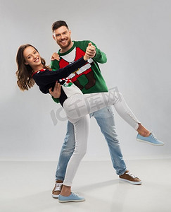 圣诞节，人们和节日的概念-幸福的情侣在丑陋的毛衣派对上跳舞。一对情侣在圣诞丑陋毛衣派对上跳舞