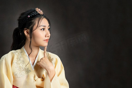 韩服图腾摄影照片_演播室里穿着传统韩服(韩服)的韩国女子。美丽的韩国文化。