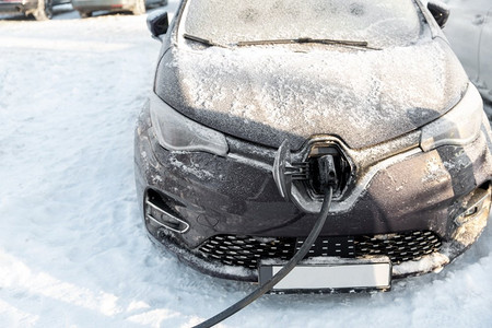 冬季能源摄影照片_车辆、动力和绿色能源概念—电动汽车充电电池在冬季特写镜头。冬季电动汽车充电特写