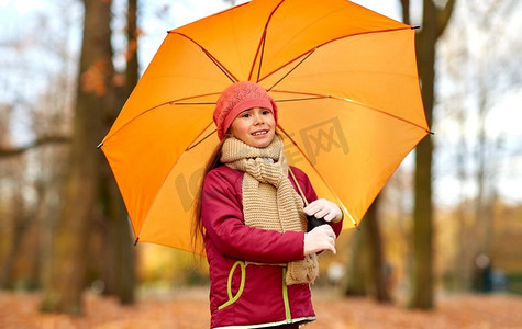 童年，季节和天气概念—快乐的小女孩与伞在秋天公园。快乐的小女孩与伞在秋天公园