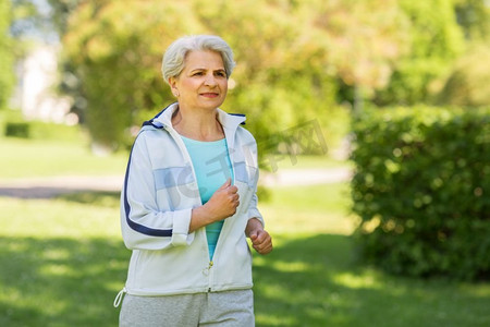 健身、运动、健康的生活方式理念--老年女性沿着夏季公园跑步。沿着夏季公园跑步的老妇人