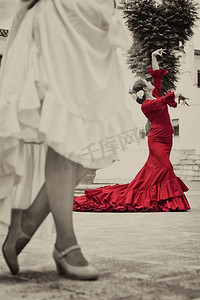 在城镇广场跳舞的妇女传统西班牙弗拉门戈舞者的深褐色色调照片，焦点是在红色礼服的舞者
