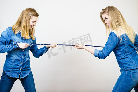 两个女人因互相生气而吵着拉绳子。糟糕的竞争关系..两个女人吵着拉绳子