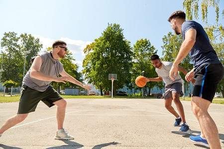 体育、休闲游戏和男性友谊概念—一群男人或朋友打街头篮球。一群男性朋友打街头篮球