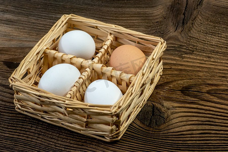 母鸡鸡蛋放在一个柳条篮子在一个老式的木板桌子上。乡村厨房静物准备复活节。