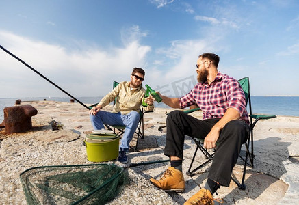 休闲与人际概念—男性朋友在码头钓鱼、喝啤酒。男性朋友钓鱼和喝啤酒在海上码头
