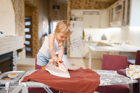 小宝宝在厨房熨衣服。孩子在家做家务。年轻的家庭主妇打扫房子