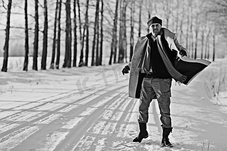 穿着大衣/冬季风格的时髦男子，在冬季风景的背景下行走，下雪的天气，保暖的衣服