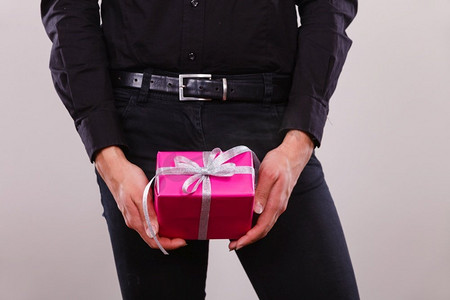 人们庆祝圣诞节，爱和幸福的概念—年轻人手里拿着礼物粉红色礼品盒。男子手拿礼物粉红色礼品盒