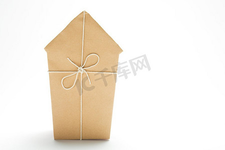 房子抵押摄影照片_工作室拍摄的模型房子包裹在棕色的纸和捆绑与字符串