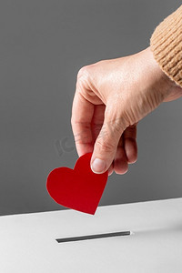 慈善、爱心、情人节&S日概念--将红心放进捐赠箱的特写。手把红心放进捐赠箱