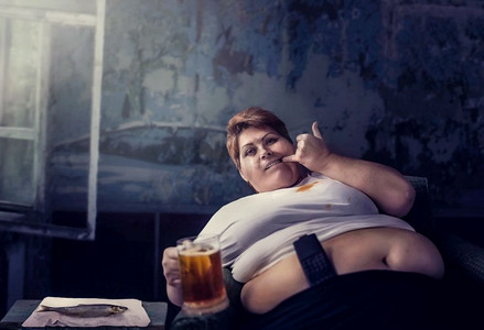 超重的女人手里拿着一杯啤酒，肥胖。不健康的生活方式，肥胖的女性。超重的女人喝着一杯啤酒，肥胖
