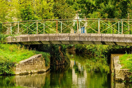 马镇摄影照片_法国的库隆镇。河景与旧石桥。Deux Sevres，New Aquitaine地区。旅游地。有桥的河法国库隆镇