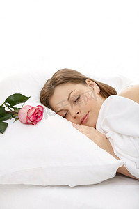 睡在床上的女孩的肖像，枕头上放着一朵玫瑰